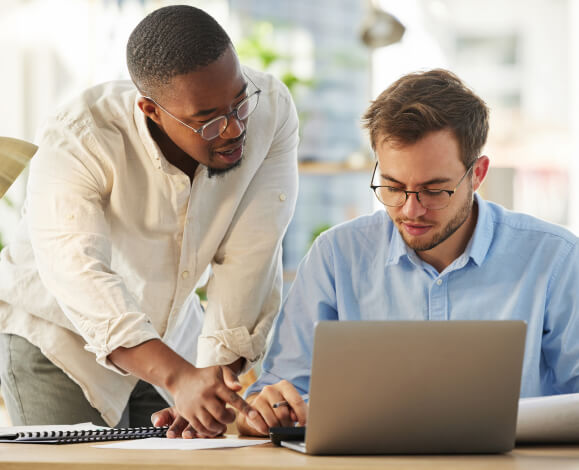 Teacher helping student working on laptop