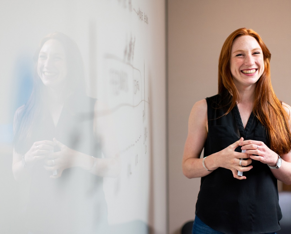 Woman standing in front of a whiteboard smiling